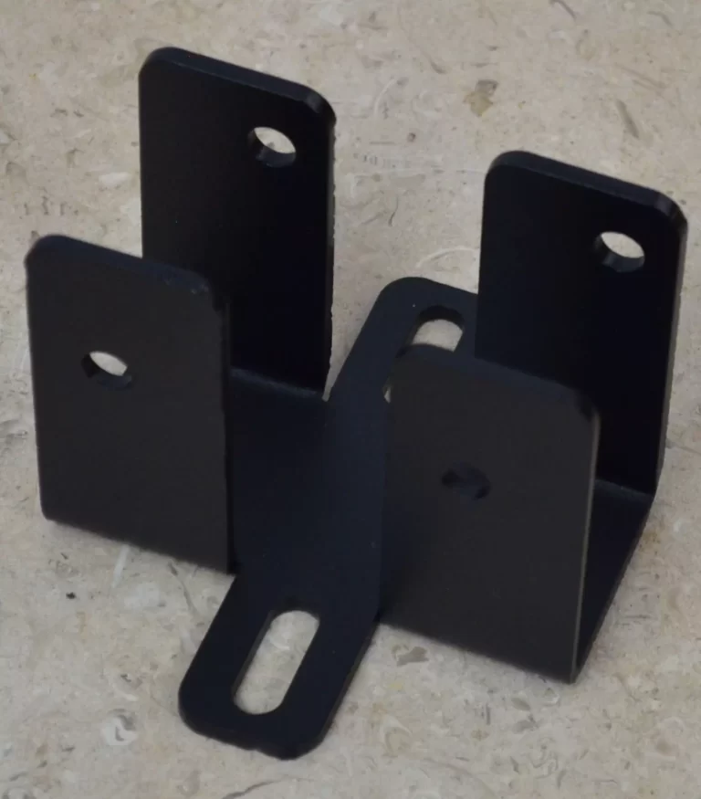 The DIY Rafter Tie Bracket is a black metal connector with five upright tabs, each with a hole or slot, arranged in a cross shape. Shown on a beige textured surface, it’s ideal for versatile roof bracket installations.