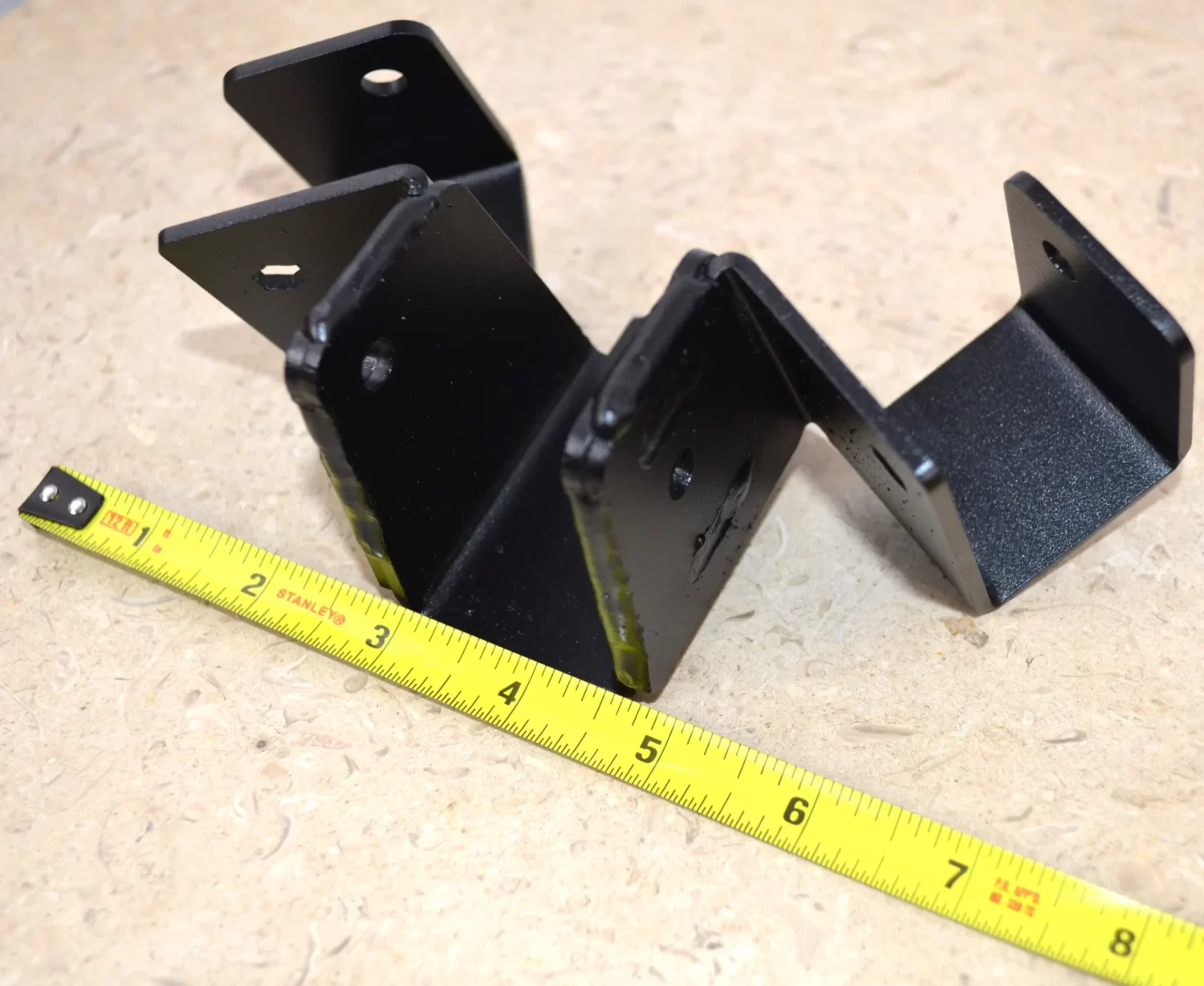 DSC_0114 This black metal bracket features a unique design for stable attachment, commonly used in construction projects for holding equipment securely in place