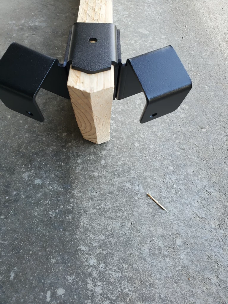a metallic bracket is securely fastened to a wooden beam, providing sturdy support in a construction workshop environment, demonstrating functional design.