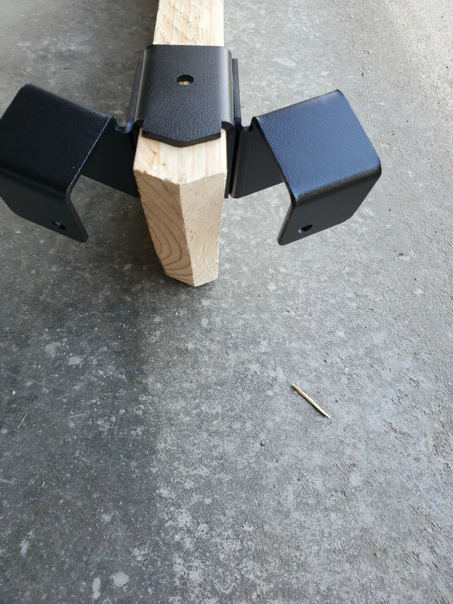 20230510_160753 a metallic bracket is securely fastened to a wooden beam, providing sturdy support in a construction workshop environment, demonstrating functional design.