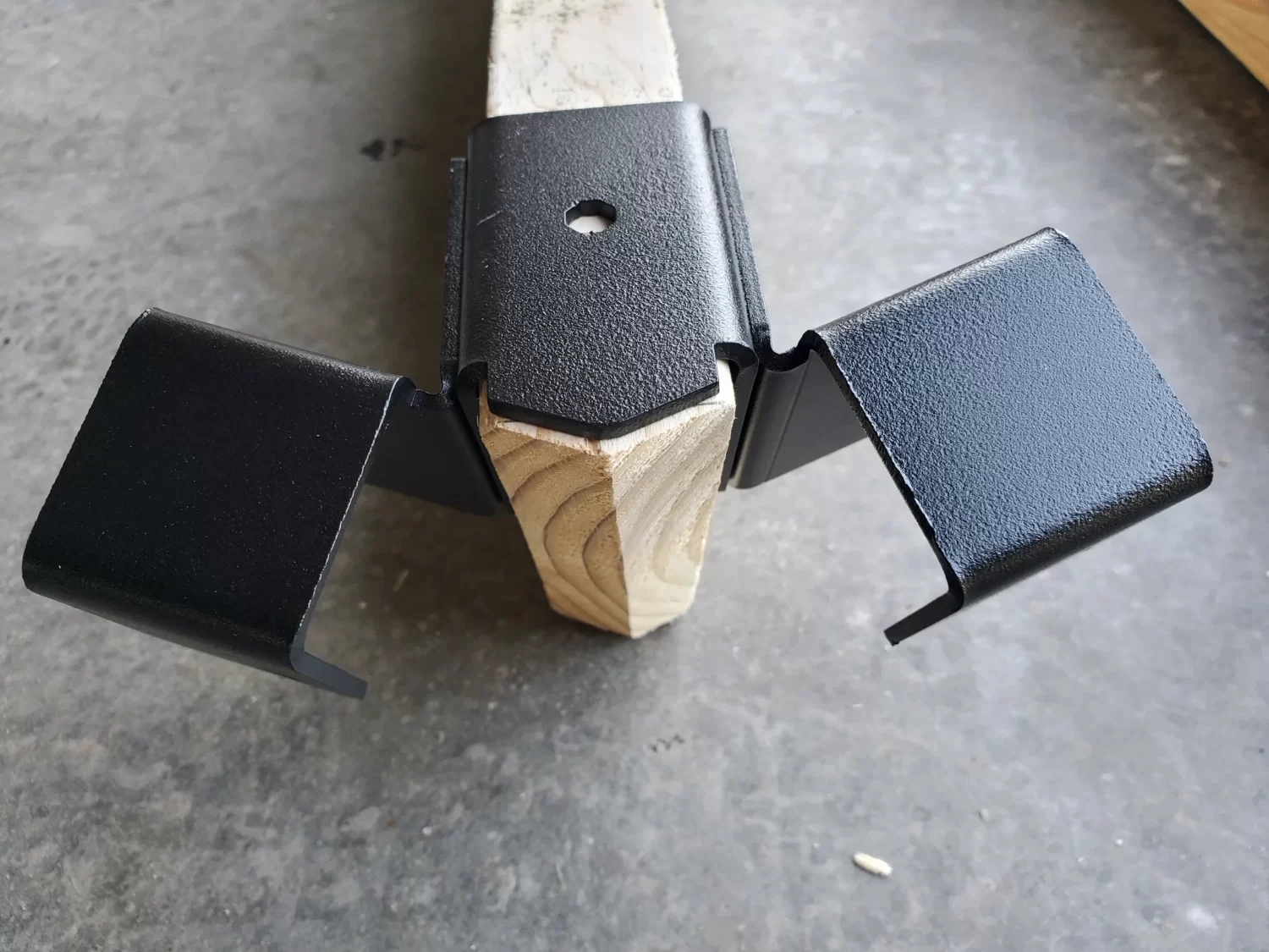 20230510_160815 a metallic bracket is securely fastened to a wooden beam, providing sturdy support in a construction workshop environment, demonstrating functional design.