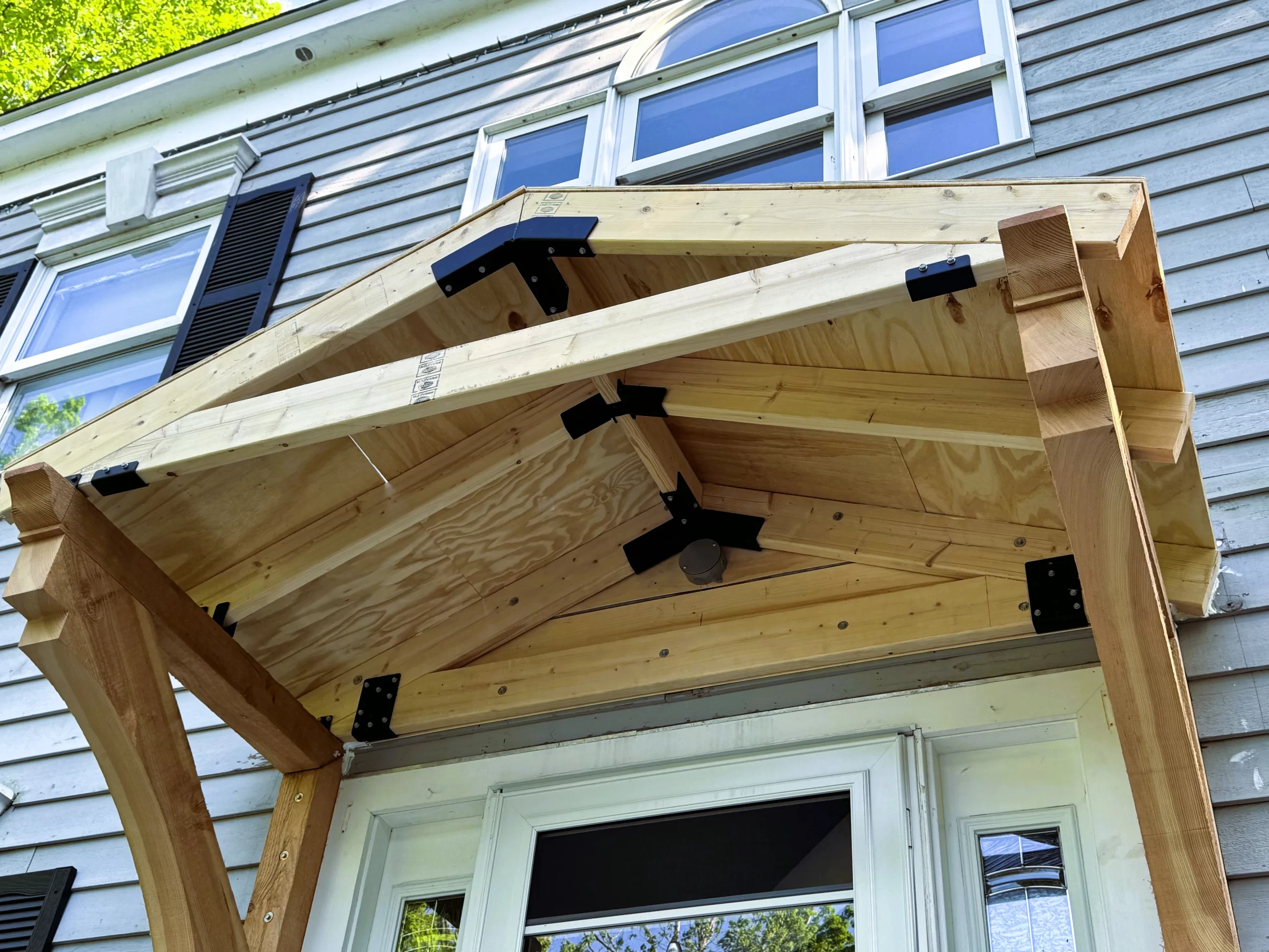 a front portico under construction, showing metal brackets making lumber joints.